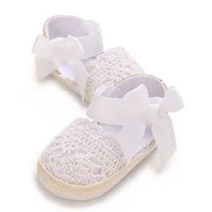 Detailed view of elegant white lace baby sandals featuring soft ribbon bows and woven soles