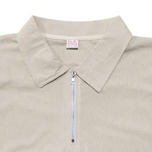 Detailed view of beige ribbed polo shirt collar with silver half-zip design