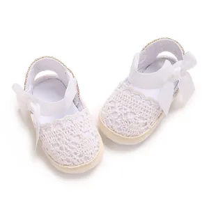 Macro view of delicate white lace pattern and ribbon bow on baby girl summer sandals