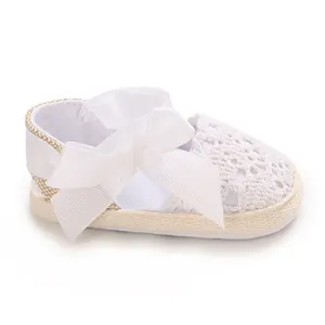 Detailed macro view of white baby girl lace sandals featuring a delicate ribbon bow.