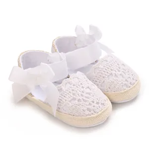 Detailed view of white crocheted lace baby sandals with soft elegant ribbon bows.
