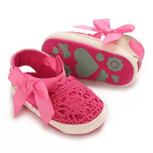 Macro view of pink crocheted baby girl sandals with decorative bow and patterned fabric sole