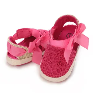 Detailed view of the pink lace crochet pattern and satin ribbon bow on baby sandals