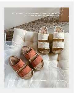 Detail view of retro girls' soft-sole sandals featuring woven straps with cute pom-pom trim.