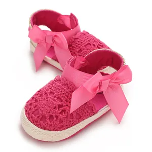Close-up detail of pink infant lace crochet sandals with large decorative ribbon bows