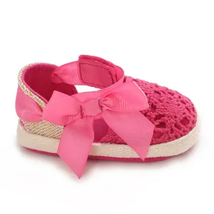 Close-up detail of soft-soled pink lace baby girl sandals with a decorative ribbon bow