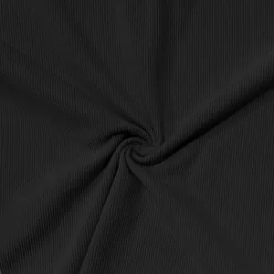Gros plan sur la texture du velours côtelé noir montrant des côtes fines et un drapé souple