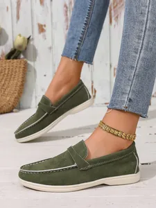 Detaillierte Nahaufnahme von grünen Wildleder-Loafers mit weißen Ziernähten oben.