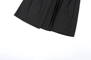 Close-up detail van de zoom van een zwarte maxi-jurk met elegante stofplooien