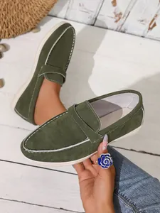 Nahaufnahme von grünen Wildleder-Slippern im britischen Stil mit weißen Kontrastnähten.