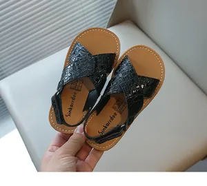 Primo piano di sandali neri per bambini con stampa coccodrillo e velcro.