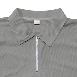 Detailed close-up showing the texture of gray ribbed polo shirt with metal zipper and size label