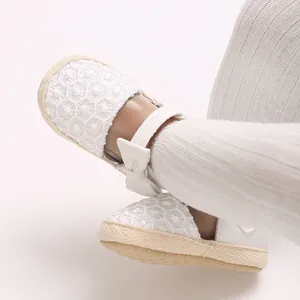 Close-up view of white lace baby girl princess shoes with bow detail worn by a child model