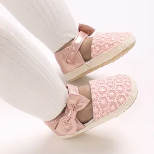 Close-up of pink baby shoes with lace and bow, worn with white ribbed stockings.