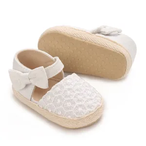 Detailed view of white baby girl princess shoes featuring decorative bow and floral lace