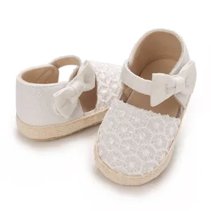 Close-up of white baby girl princess shoes with lace pattern and bow detail