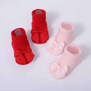 Primer plano de lindos calcetines para bebé en rojo y rosa con grandes lazos decorativos