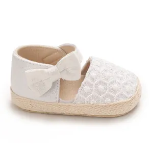 Detailed close-up view of a white baby girl princess shoe with lace and a big bow