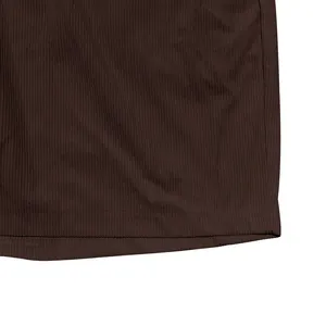 Gedetailleerd macrozicht op bruine corduroy stoftextuur en zoom van herenshorts.