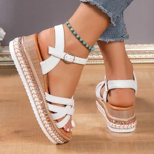 Detalle de sandalias de plataforma blancas con tiras cruzadas, strass y cuña trenzada