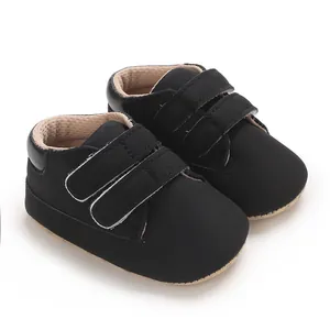 Détail en gros plan de baskets noires pour bébé avec doubles lanières auto-agrippantes.