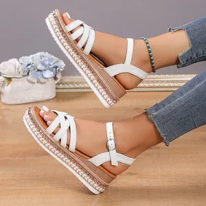 Primer plano de sandalias blancas con plataforma, pedrería y cuña de esparto trenzada