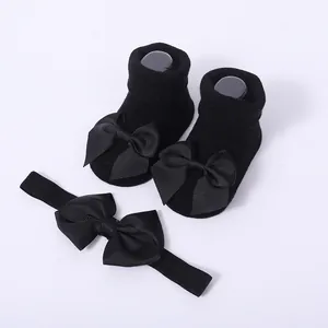 Detalle del conjunto de calcetines negros para bebé y diadema a juego con lazos grandes