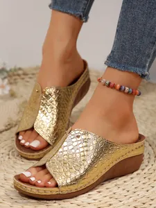 Close-up of gold snakeskin peep-toe wedge sandals for women featuring metallic rivets