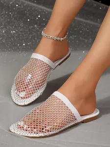 Detail van sprankelende strass-gaas op elegante witte platte muiltjes voor dames