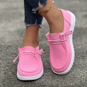 Dettaglio ravvicinato di mocassini in velluto rosa con lacci decorativi e suole bianche resistenti.