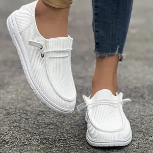 Primo piano di mocassini bianchi in velluto a coste con design slip-on casual.