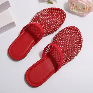 Macrodetail van elegante rode mesh slippers met fonkelende strass-accenten.
