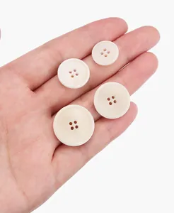 Macro shot of four-hole beige natural tagua nut buttons in various sizes held in hand