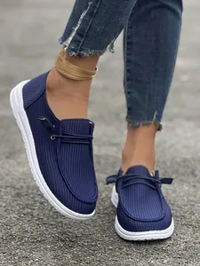 Primo piano di mocassini blu navy con suole bianche testurizzate indossati all'aperto
