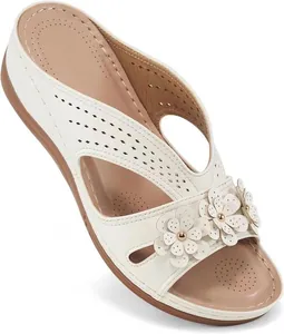 Detalle de sandalias con cuña blancas con flores de cuero y patrones cortados a láser