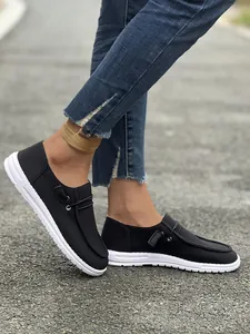 Primo piano di mocassini slip-on neri a coste da donna abbinati a jeans blu su strada urbana
