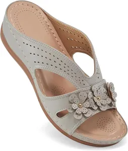 Detalle de patrones florales calados en sandalias de cuña gris claro con punta abierta