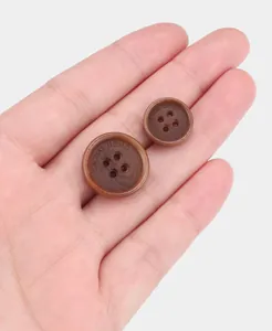 Close-up of brown Tagua nut buttons with Casual Uomo engraving on a palm