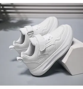 Vista lateral de zapatillas blancas para niños en cuero sintético con suela gruesa y velcro.