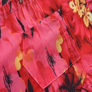 Primer plano del bolsillo de una camisa hawaiana con estampado tropical rojo vibrante.