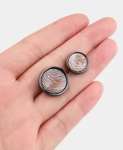 Nahaufnahme strukturierter natürlicher Perlmuttknöpfe in einem Metallrahmen in der Hand