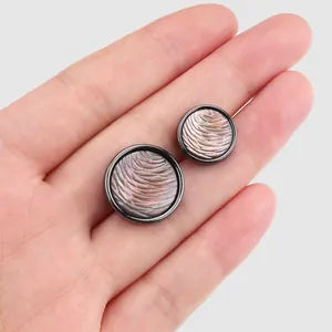 Natürliche Schwarzlipp-Muschelknöpfe mit strukturierter irisierender Einlage in der Hand