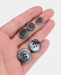 Close-up detail of natural dark shell buttons in multiple sizes for high-end garments