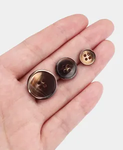 Macro view of three brown natural shell 4-hole buttons for suits in different sizes
