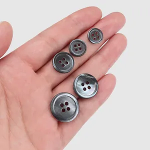 Natural high-grade grey shell buttons in various sizes for suits and sweaters shown on hand