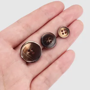 Brown marbled natural shell buttons in three sizes for suits, held in hand display