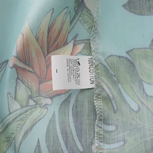 Primer plano de una camisa hawaiana de 100% algodón con etiqueta de lavado y costura.
