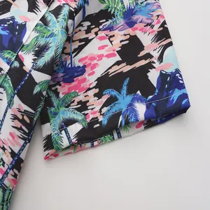 Detalle de la manga de una camisa hawaiana con estampado tropical de palmeras y atardecer