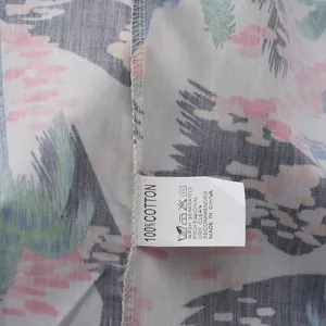Primer plano del tejido de algodón 100% y etiqueta de cuidado en camisa hawaiana