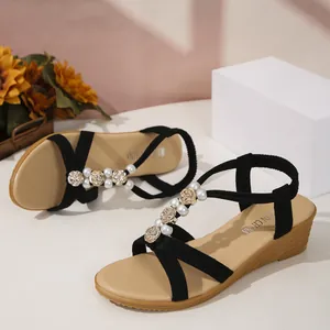 Detailansicht eleganter Perlen- und goldener Rosenanhänger an schwarzen Keilsandalen
